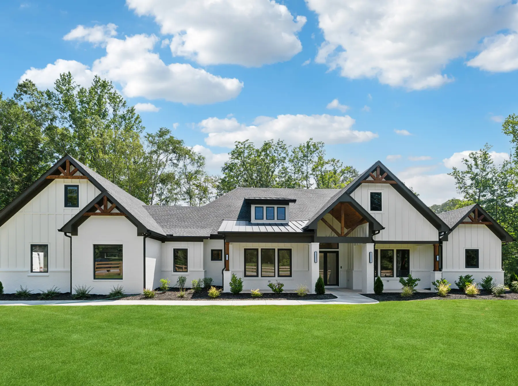 Front elevation of Project 938, a white brick and board-and-batten farmhouse with black trim and cedar gable trusses